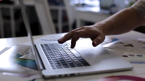 A adam çalışma üstünde a laptop ve grafik analiz eder — Stok video