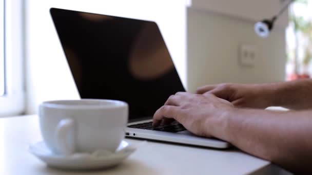 Hombre trabajando con un portátil en la oficina y bebiendo café — Vídeos de Stock