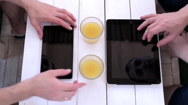 Deux hommes tapent sur une tablette dans un café. Vue d'en haut — Video