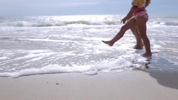 Жінка з маленькою дівчинкою, що йде морем — стокове відео
