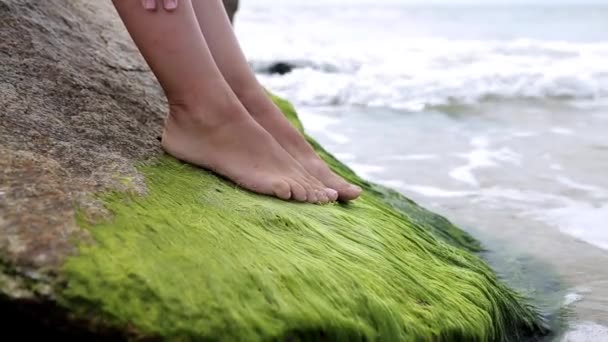 Ноги молодої дівчини на камені біля моря — стокове відео