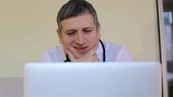 Доктор дивиться на ноутбук і посміхається — стокове відео