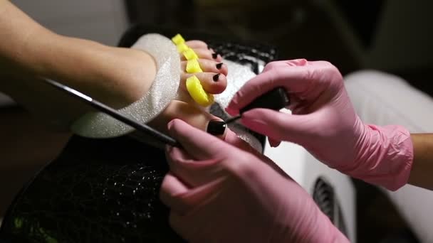 Nail pedicure technician performing procedure for foot care in beauty salon
