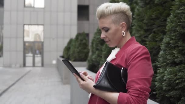 ビジネスセンターの近くに立ち チャットルームでチャットしている赤いジャケットのビジネス女性 — ストック動画