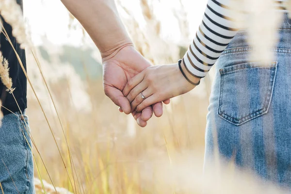 Jong stel hand in hand in een tarweveld — Stockfoto