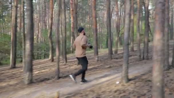 Man Met Zwarte Pet Met Camera Handen Rennend Het Bos — Stockvideo