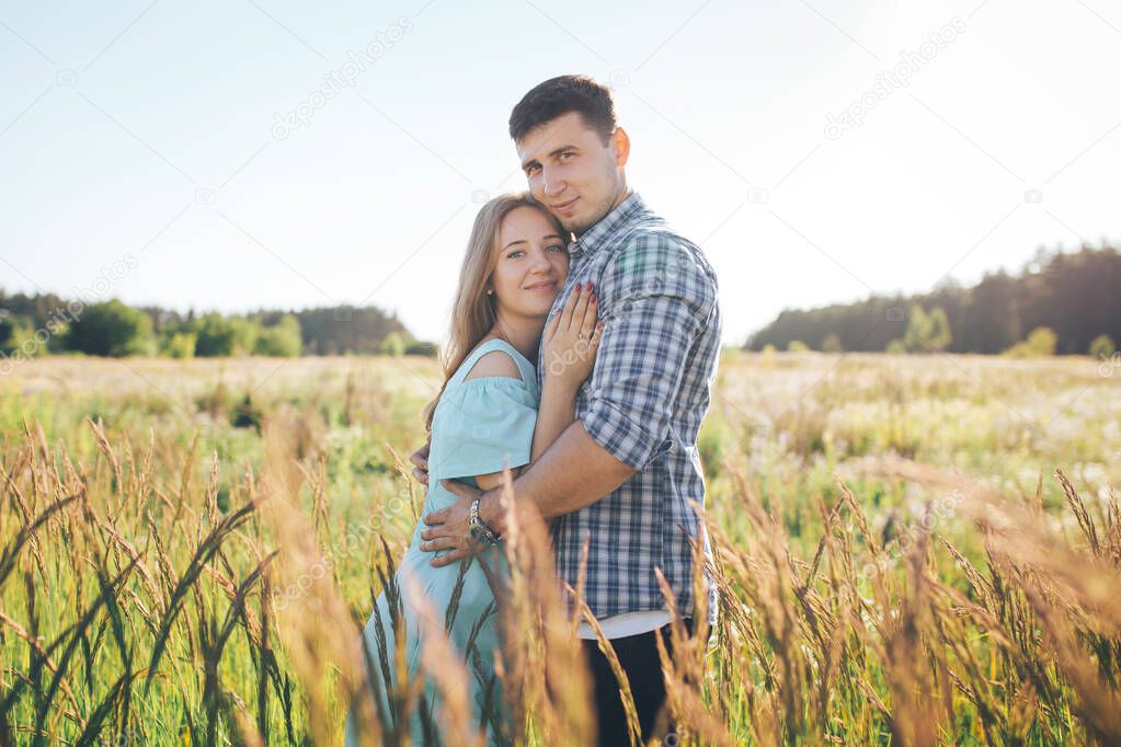 The guy kisses the girl's forehead in a wheat field