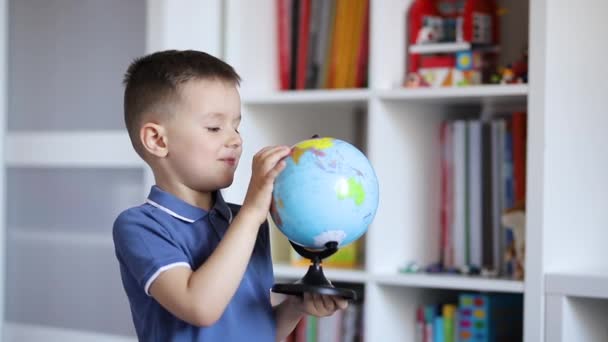 Een Kind Onderzoekt Een Wereldbol Terwijl Hij Hem Zijn Handen — Stockvideo