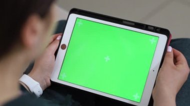 Omzunun arkasından tabletin yeşil ekranına bak. Kız tabletten bir şey izliyor.