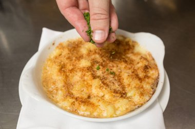 Fırında makarna peynirinin üzerine serpilmiş doğranmış taze maydanoz.