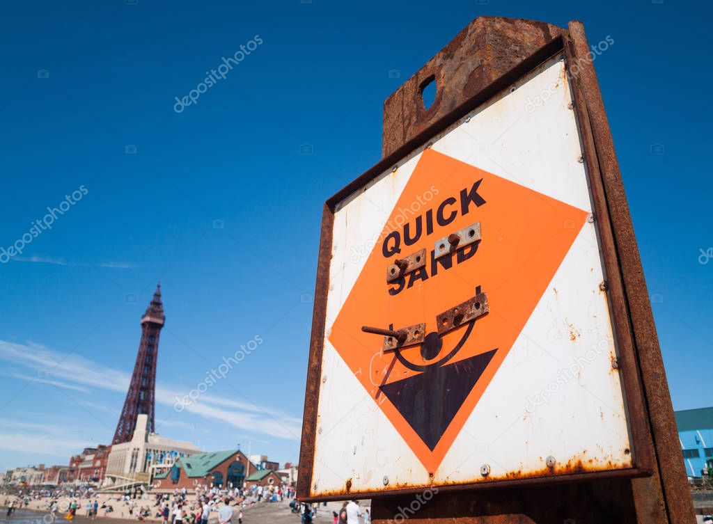 Blackpool, England, 05/05/2015, Danger quick sand warning hazard sign ,on a rusty metal beam on Blackpool beach with the tower in the background.