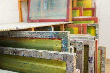 Baskıya hazır ahşap rafta saklanan ipek ekranlı baskı ekranları.