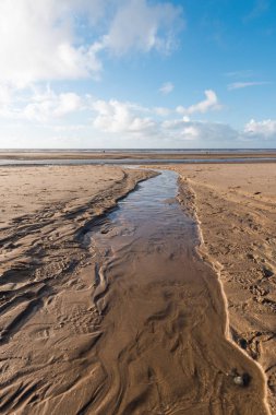 Güzel mavi gökyüzü ve dokulu kum, plajda serin güneşli kışlar gününde