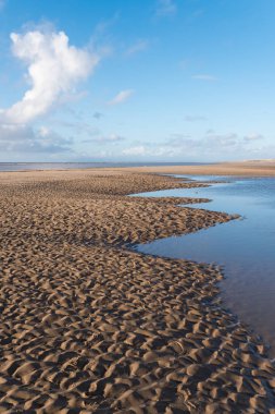 Güzel mavi gökyüzü ve dokulu kum, plajda serin güneşli kışlar gününde