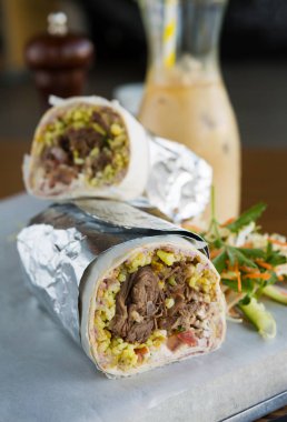 Meksika rendelenmiş sığır eti kahvaltı burrito yarısında buz kahve ile servis dilimlenmiş.