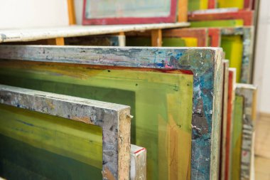 Baskıya hazır ahşap rafta saklanan ipek ekranlı baskı ekranları.