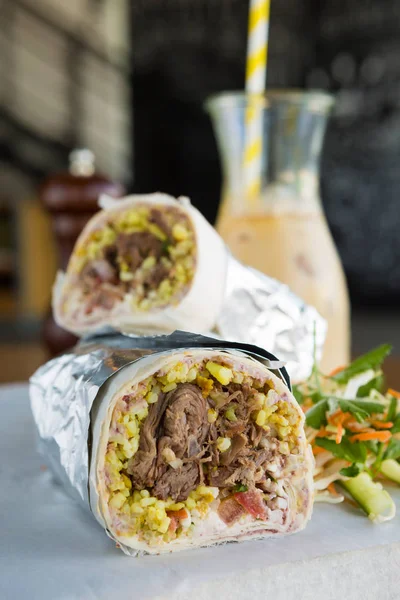 Mexican shredded beef breakfast burrito sliced in half served with ice coffee.