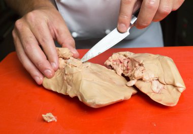 Kırmızı kesme tahtası üzerinde kaz ciğeri hazırlama ve dedamarlama.