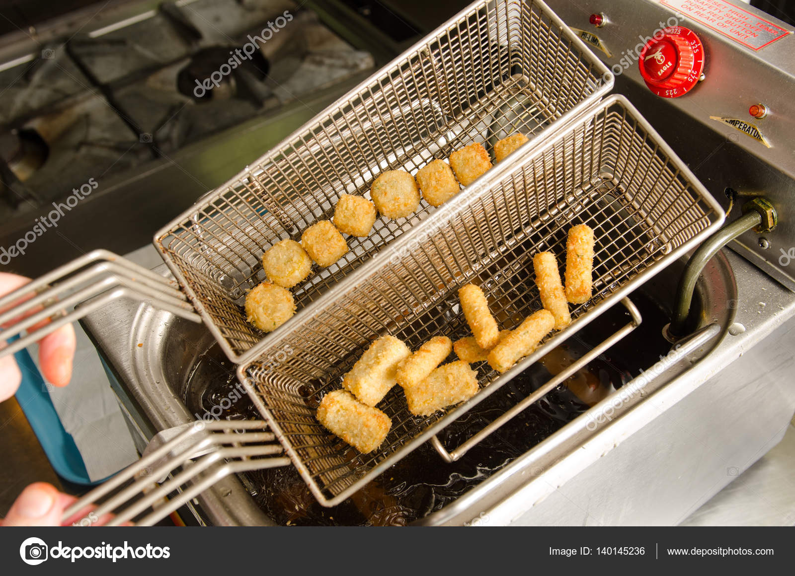 A silver deep pan industrial kitchen oil fryer, with golden oil