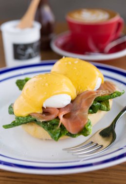 Yumurta benedict ve taze somon sunmaktadır hollandaise sos ve bir kahve eşliğinde hafifçe kızarmış kek üzerinde.