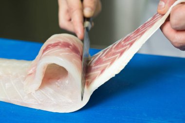 Keskin bir bıçak kullanarak mavi kesme tahtası üzerinde taze bir balıktan kemiği filetolama ve çıkarma.