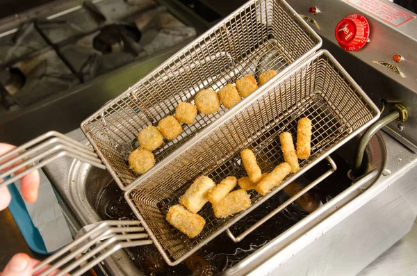 A silver deep pan industrial kitchen oil fryer, with golden oil, bubbling and frying potatoes — Stock Photo, Image