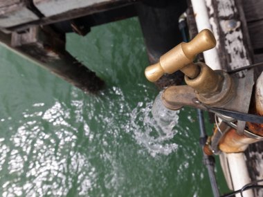 Bir balıkçı iskelesindeki bir balıkçı temizleme istasyonunda sızdıran eski paslı musluk 