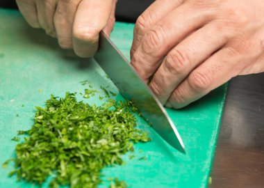 Organik taze maydanoz ince yeşil bir kesme tahtası üzerinde doğranmış olmak.