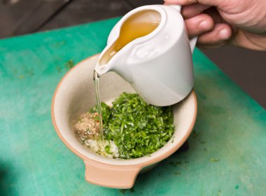 Sızma zeytinyağı Organik taze kesilmiş maydanoz, sarımsak ve otlar bir kase içine dökülür.