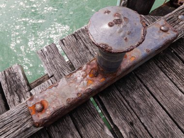 Bir balıkçı iskelesi üzerinde, tekne demirleme için kullanılan canlı, paslı, eski metal bollard sonrası 