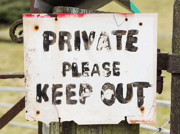 Old creepy private keep out sign on a wooden post.