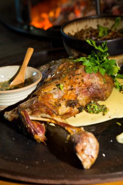 Lezzetli ücretsiz aralığı bir rustik metal bir sıcak açık kömür ateşin yanında tabakta keçi omuz kavrulmuş. Taze maydanoz ile hizmet.