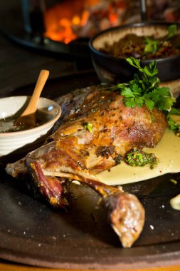 Lezzetli ücretsiz aralığı bir rustik metal bir sıcak açık kömür ateşin yanında tabakta keçi omuz kavrulmuş. Taze maydanoz ile hizmet.