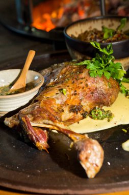 Lezzetli ücretsiz aralığı bir rustik metal bir sıcak açık kömür ateşin yanında tabakta keçi omuz kavrulmuş. Taze maydanoz ile hizmet.