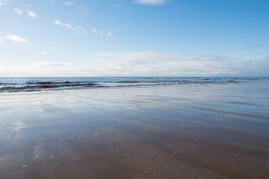 canlı mavi gökyüzü ve yansıması ile, gün batımında bir plaja akan rahatlatıcı ve nazik sakinleştirici dalgalar