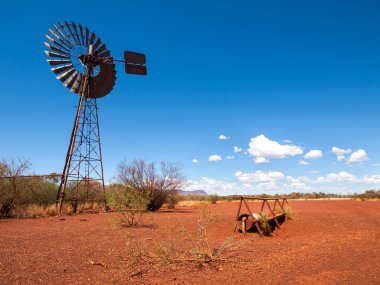 bir eski paslı Rüzgar Türbini ve sığır Besleyici, Avustralya outback bush sert kurak kırmızı manzara.