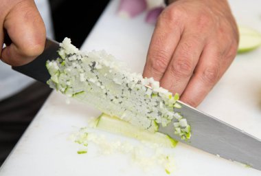 Taze organik yeşil elma, ince küpler bir beyaz kesme tahtası üzerinde kesme bıçağı.