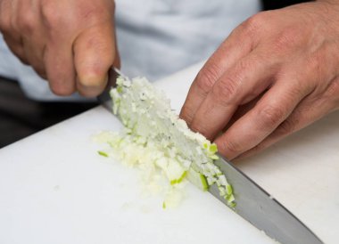 Taze organik yeşil elma, ince küpler bir beyaz kesme tahtası üzerinde kesme bıçağı.