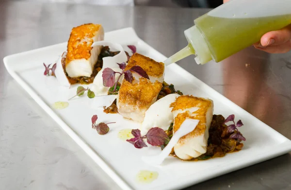 Taze pan katılaşmış, gevrek altın cod curried karnabahar, ıspanak ve patates üzerinde servis fileto, balık. Bir güzel deniz ürünleri yemek.