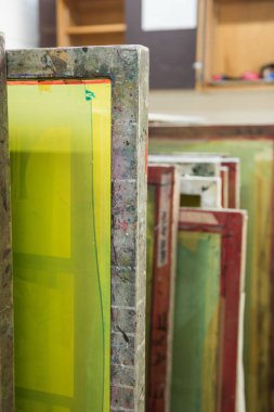 Baskıya hazır ahşap rafta saklanan ipek ekranlı baskı ekranları.