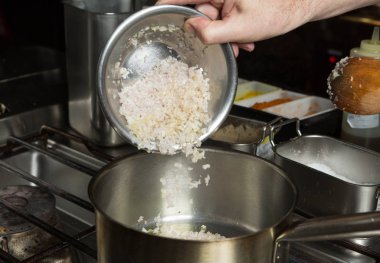 Kıyılmış sarımsak ve ince dilimlenmiş soğan zeytinyağı bir metal kızartma tavası düştü. Adım adım tarifi pişirme tarafından.
