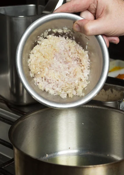 Мясной чеснок и мелко нарезанный лук сбрасывают в металлическую сковородку с оливковым маслом. Шаг за шагом рецепт приготовления пищи — стоковое фото