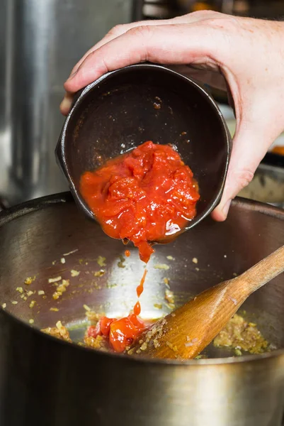 Свеженарезанная органическая виноградная лоза созрела помидоры, которые были сброшены в горячую сковороду в рамках стадии рецепта . — стоковое фото