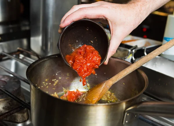 Свеженарезанная органическая виноградная лоза созрела помидоры, которые были сброшены в горячую сковороду в рамках стадии рецепта — стоковое фото