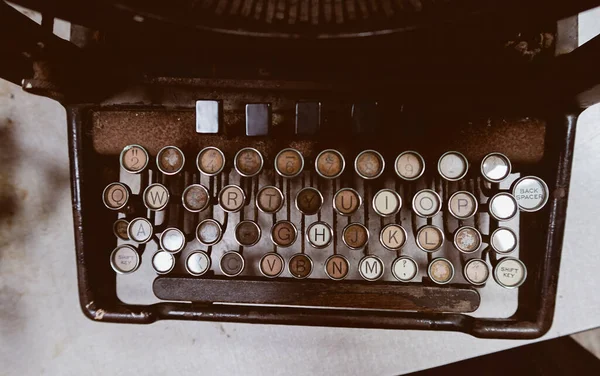 A rusty dirty old decaying vintage antique type writer sat in an office on a table. Scary abandoned horror story typewriter with orange and brown rust. story telling equipment