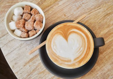 Kremalı kahveyle dolu güzel, kahverengimsi, sıcak bir kahve fincanı. Kahveli, ahşap bir kahve dükkanında servis ediliyor. Organik adil ticaret kahvesi yukarıdan çekilmiş.