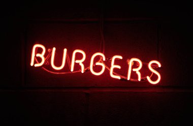 Antika bir Amerikan tarzı neon tabelalı reklam burgeri. Kırmızıyla karanlığı aydınlatan neon tüplü karanlık bir ortam. Gıda reklamcılığı ve gıda sektöründe tabela