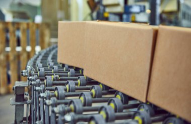 Tam otomatik bir çevrimiçi perakende satış deposunda endüstriyel paten kayışında teslimat paketleri. Ticari çevrimiçi satışları insan işgücü olmadan kolayca hareket ettirebilmek için paten taşıyıcı..