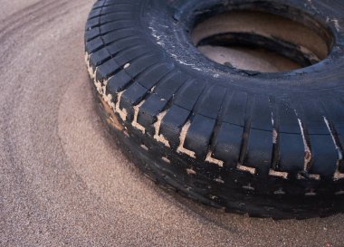Lastik kirli eski araç lastiği kumlu, lüks bir plaj istikametinde kıyıya vurmuş. Çevresel plastik kirliliği sorunu dünya haberlerine neden oluyor. Plajlarda sağlık felaketi.                            