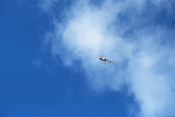 A seaside nautical search and rescue helicopter with rotating blades in the distance with a vivid bright blue sky and clouds. Rescue helicopter and rescue teams are brave.